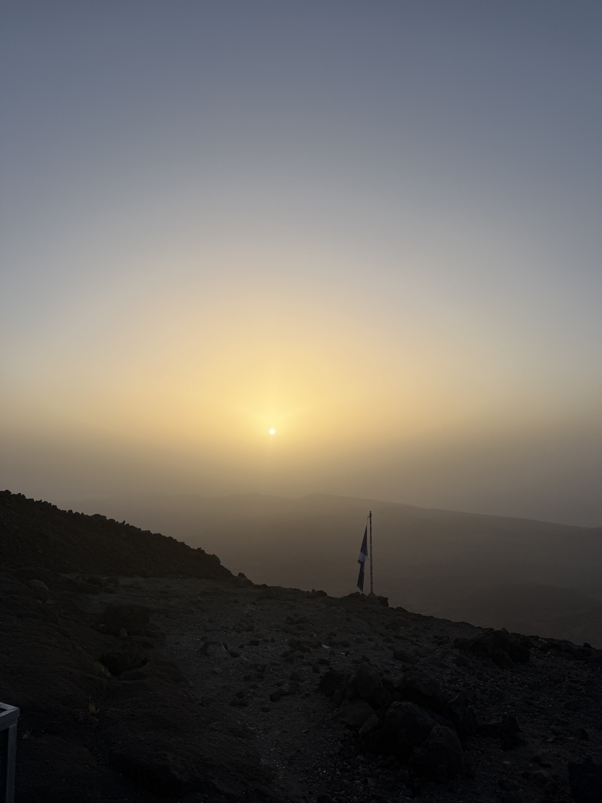 Sunrise glow on the upper trail of Mount Teide with a trail marker